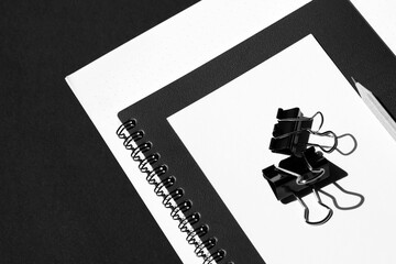 Spiral Notebook, Cards, Pencil, Binder Clips on Black Background. Monochrome Business Flat lay. 
