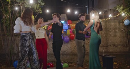 Friends are having a birthday party and dancing in the backyard at night. They are celebrating, having fun, and enjoying life. - Powered by Adobe