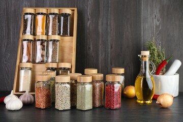 Different spices and glass jars on grey wooden table