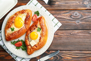 Tasty khachapuri with cheese and eggs served on wooden table, flat lay. Space for text