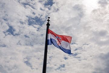 Croatian National Flag Flies Against Cloudy Sky on Tall Flagpole