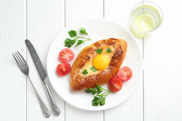 Tasty khachapuri with cheese and egg served on white wooden table, flat lay