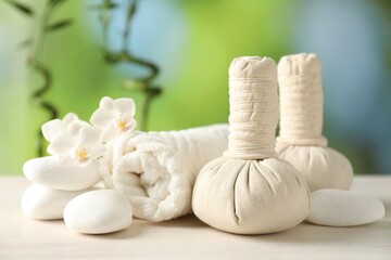 Beautiful spa composition with herbal bags on white wooden table against blurred background, closeup