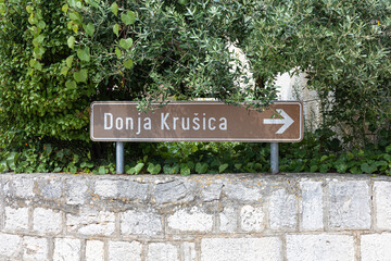 Donja Krusica Road Sign Amid Lush Greenery and Stone Wall Backdrop, Solta, Croatia