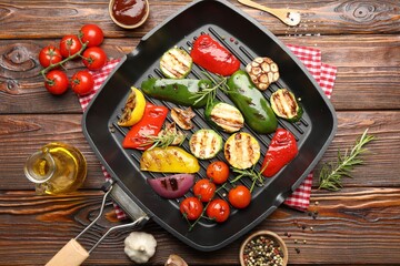 Pan with grilled vegetables and spices on wooden table, flat lay