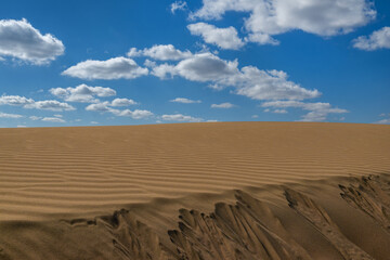 Clouds in the blue sky above a sand dune