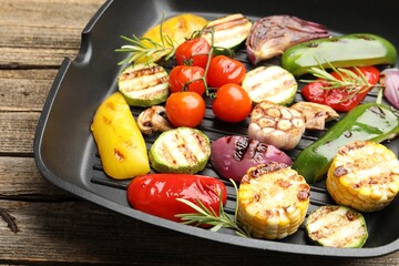 Pan with grilled vegetables and spices on wooden table, closeup