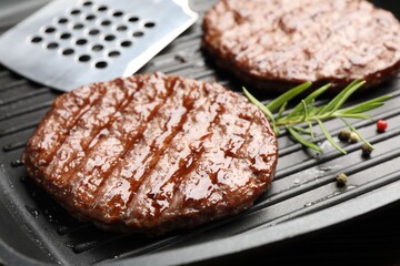 Pan with grilled patties, spices and slotted spatula, closeup