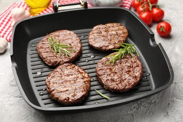 Pan with grilled patties, tomatoes and spices on grey table, closeup