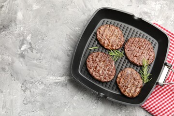 Pan with grilled patties and rosemary on grey table, top view. Space for text