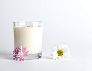 A glass-encased candle sits next to a pink and white daisy. A white background
