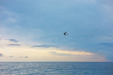 Airplane flying above sea in beautiful blue sky, low angle view