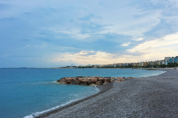 Beautiful view of wavy sea, city and pebbles on beach