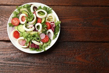 Delicious salad with squid rings and vegetables on wooden table, top view. Space for text