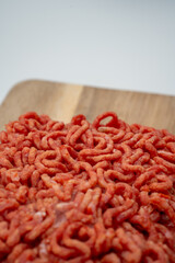 Top-down view of frozen minced beef. The beef is with vegetables in the dough on wooden cutting board with white background