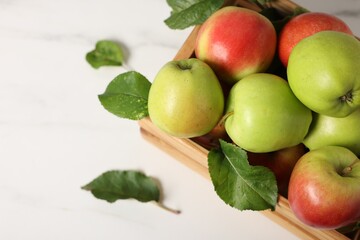 Fresh ripe apples in crate on white table, closeup. Space for text