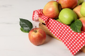 Fresh ripe apples in crate on white table, closeup