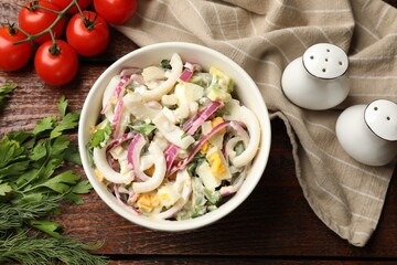 Tasty salad with squid rings, onion and eggs served on wooden table, flat lay