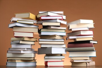 Many stacked books on table against brown background
