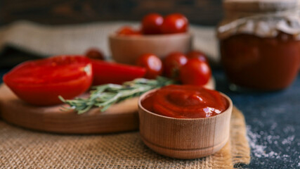 Ketchup and tomatoes with rosemary on a wooden board