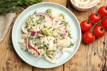 Tasty salad with squid rings, onion and eggs served on wooden table, flat lay