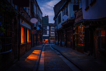 Fototapeta premium York city's historic alley at sunrise, featuring well-preserved landmark architecture and medieval timber-framed buildings, a popular tourist attraction and shopping area in Yorkshire, England.