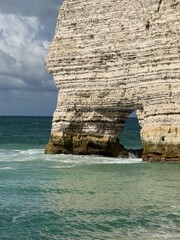 Cliffs of Étretat in Normandy, France during daytime, with natural rock arch and sea view framed...