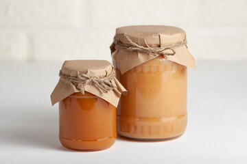 Two jars of apple jam in rustic wrapping on a light background