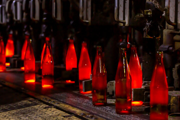 Glass factory, production of glass containers. Molten glass is blown into molds. Robotics in industry. Modern technologies, robotic machines produce products. Technological work at the plant.
