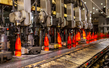 Glass factory, production of glass containers. Molten glass is blown into molds. Robotics in industry. Modern technologies, robotic machines produce products. Technological work at the plant.