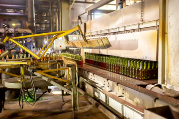 Glass factory, production of glass containers. Molten glass is blown into molds. Robotics in industry. Modern technologies, robotic machines produce products. Technological work at the plant.