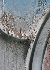 Close-up of old peeling paint on a wall surface. Weathered, cracked and flaking layers create a textured and distressed background.