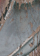 Close-up of old peeling paint on a wall surface. Weathered, cracked and flaking layers create a textured and distressed background.