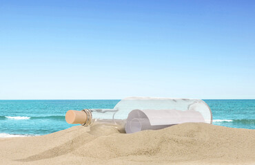 Obraz premium Corked bottle with rolled letter inside on sand near sea