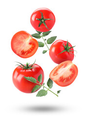 Fresh ripe tomatoes and green leaves falling against white background