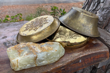 Nature morte avec plateau et bassine en laiton et une pierre brute d'opale posés sur une vieille table en bois