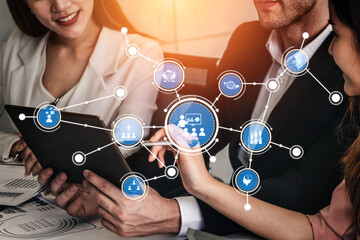 Business professionals collaborating with digital technology and icons representing communication, teamwork, and data management in a modern office setting. Tessel.