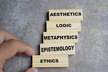 5 types of philosophy. Aesthetics, logic, metaphysics, epistemology and ethics on stacked wooden cubes on the table. Business and finance concept