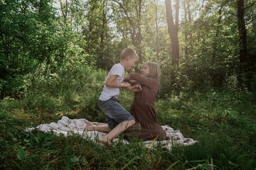 A young brother and sister enjoy a picnic together in a sunny park, sharing authentic moments of sibling bonding and simple outdoor joy. Pure, unfiltered family happiness