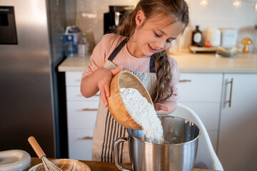 Little cute girl baking cookies in the kitchen. Homemade pastries. Cozy autumn.