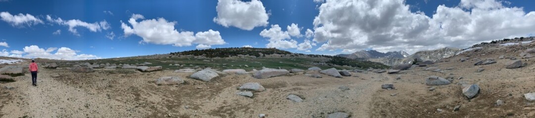 mountain landscape with blue sky and clouds - panorama with man hiking