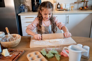 Little cute girl baking cookies in the kitchen. Homemade pastries. Cozy autumn.