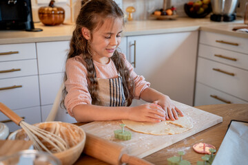 Little cute girl baking cookies in the kitchen. Homemade pastries. Cozy autumn.