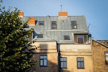 Traditional Riga apartment building with aged plaster and modernized roof, sunlight emphasizing architectural character and history, symbolizing urban heritage and timeless atmosphere of European city