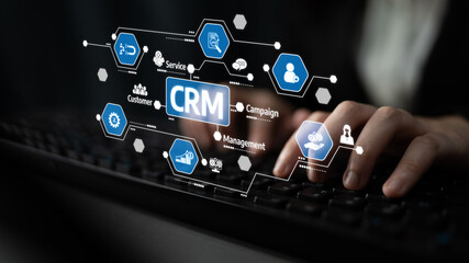 Hands typing on a keyboard with digital CRM icons illustrating customer relationship management...