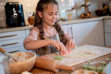 Little cute girl baking cookies in the kitchen. Homemade pastries. Cozy autumn.