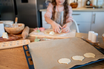 Little cute girl baking cookies in the kitchen. Homemade pastries. Cozy autumn.