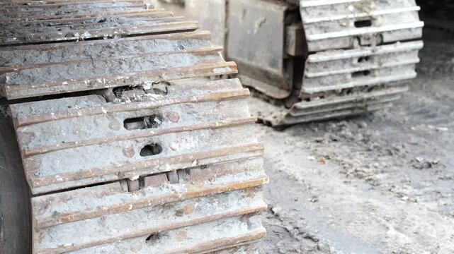 Metal crawler tracks of heavy excavator covered in dirt on industrial site showing power, durability and construction machinery used in infrastructure, mining and ground excavation projects