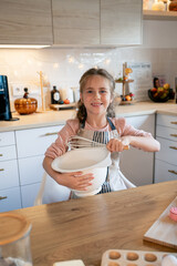 Little cute girl is beating eggs in the kitchen. Homemade baking. Cozy autumn.