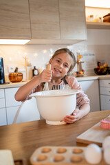 Little cute girl is beating eggs in the kitchen. Homemade baking. Cozy autumn.